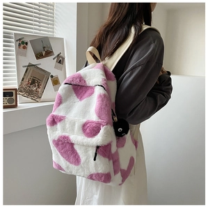 Fluffy plush backpack with pink patterns shown on model in a cozy indoor setting