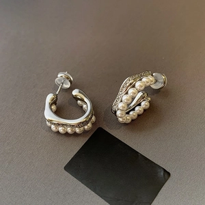 Detailed close-up of C-shaped silver earrings with delicate pearls and sparkling crystals