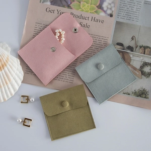 Detailed view of pink, grey-blue and olive green velvet jewelry pouches with snap buttons