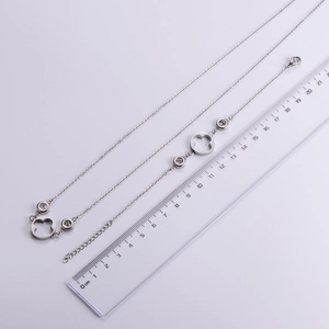 Macro detail of silver zircon clover necklace and bracelet set with measurement scale
