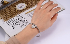 Detailed shot of silver snake chain bracelet featuring a heart pendant with pavé crystals