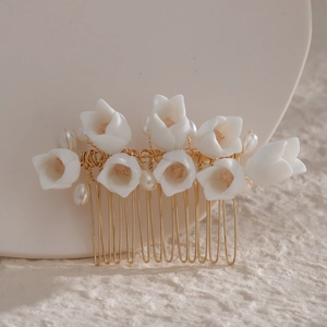 Detail of bridal hair comb with white ceramic flowers, pearls, and crystals on gold finish