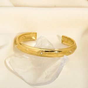 Detailed macro view of gold-plated stainless steel cuff bracelet with star engravings