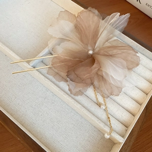 Détail d'une épingle à cheveux fleur en soie avec pompon doré et perles élégantes
