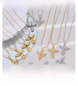 Detailed shot of 18K gold and silver phoenix wing pendants with emerald and blue sapphires
