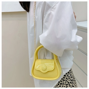 Close-up of bright yellow mini jelly bag with gold chain strap worn by a model