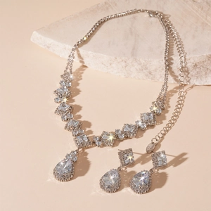 Elegant 2-piece silver zircon necklace and water drop earrings set on a warm stone base