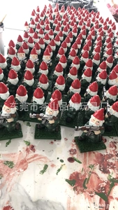 Close-up of funny garden gnome statue holding a gun with detailed red hat and green outfit