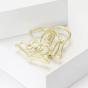 Close-up of golden alloy brooch with abstract cut-out female silhouettes in artistic style