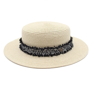 Detail of flat-top straw boater hat with tweed band and golden M-logo metal plate