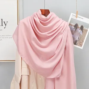Detail of pink cotton linen scarf draped elegantly on a beige blazer and wooden hanger