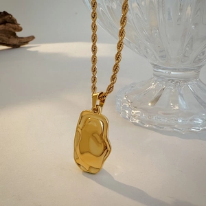 Detailed macro of 18K gold plated hammered irregular pendant with thick twist chain