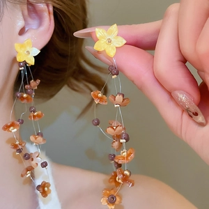 Detailed macro view of yellow resin flower earrings with pearly fringe tassels and beads