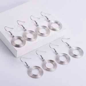 Detailed view of silver metallic spiral spring hoop earrings on a white display block