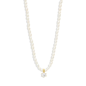 Detail of white irregular pearl necklace with a gold-tone round stone pendant focal point