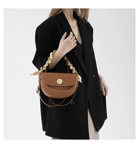 Detail view of brown saddle bag with silk scarf wrapped chain handle and gold lock