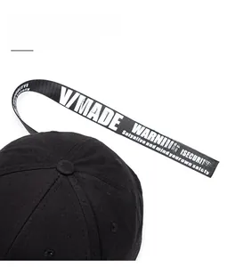 Detail of extra long black strap with white V/MADE text on a cotton baseball cap