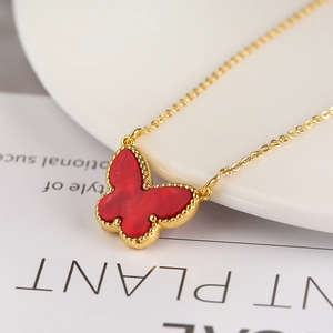 Macro shot of a red butterfly pendant necklace with a golden chain and beaded edges