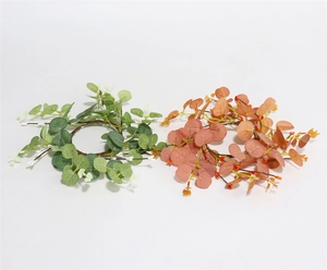 Detailed view of artificial eucalyptus and berry wreaths in green and pink-orange colors