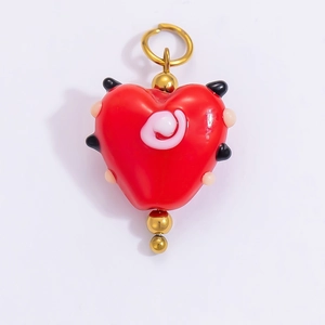 Detailed view of a red heart charm with colorful polka dots and golden metal loop