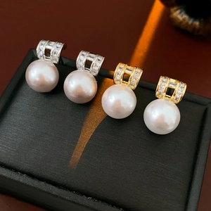 Detail of four pearl earrings with gold and silver square bases on a black jewelry box