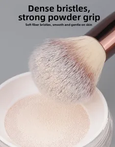 Macro shot of dense powder brush head with rose gold ferrule applying setting powder