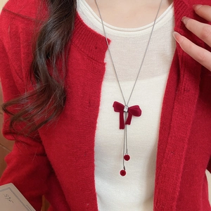 Detail of red flocked bow necklace with zircon pendant on a red knitted sweater
