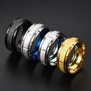 Detail of four brushed titanium rings in black, silver, gold, and blue with grooved texture