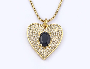 Macro shot of 18k gold plated heart pendant with black gemstone and zircon details