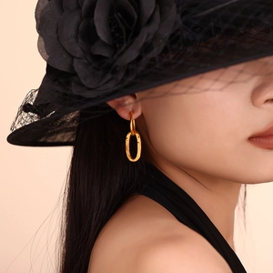 Elegant gold elongated oval hoop earrings with brushed metal texture on a female model