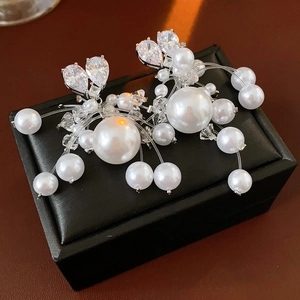 Macro detail of cascading white pearls and drop-cut zircon tassels on a black jewelry box