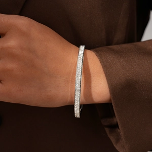 Detailed view of silver double-row pave diamond bangle on wrist with premium texture