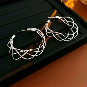 Detailed close-up of silver hollow twisted C-shape earrings with woven metal texture