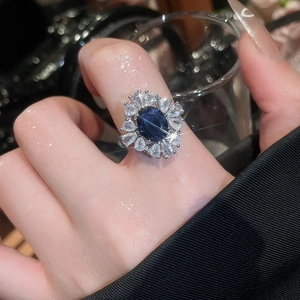 Gros plan d'une bague florale en zircon avec une pierre bleue et des cristaux clairs