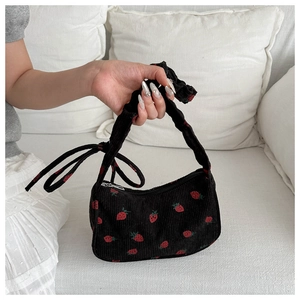Close-up of black corduroy handbag featuring red strawberry pattern and fabric handle