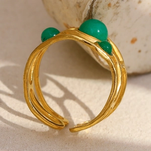 Macro side view of an 18K gold-plated open ring with green stones and hammered texture