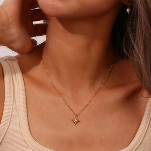 Detailansicht der goldenen Polarstern-Kette mit Perle auf einem minimalistischen Collier