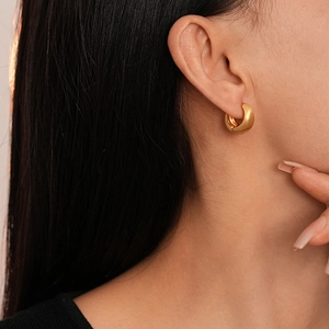 Close-up of minimalist gold plated chunky geometric hoop earrings worn by a model