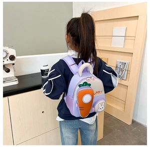 Detail of purple cartoon kids backpack with cute rabbit charm and carrot decor