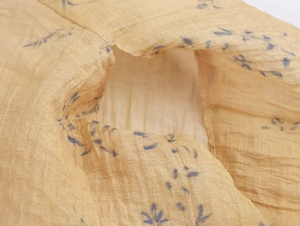 Macro detail of yellow floral fabric with delicate blue print and pleated texture