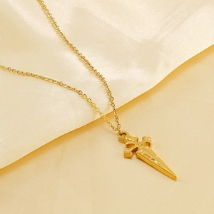 Golden stainless steel cross pendant necklace on soft yellow silk fabric background