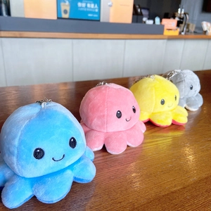 Set of four reversible plush octopus keychains in assorted colors on a wooden table