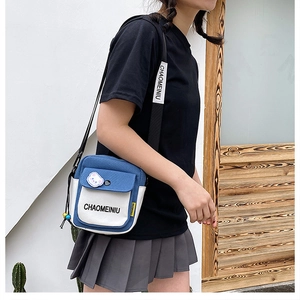 Detail of blue and white canvas crossbody bag featuring a custom strap and bear pin