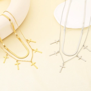 Macro detail of gold and silver double-layered cross pendant necklaces with snake chain