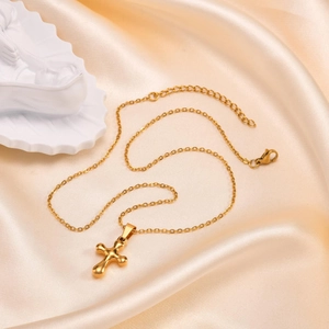 Close-up of golden cross necklace on champagne satin with artistic plaster sculpture detail