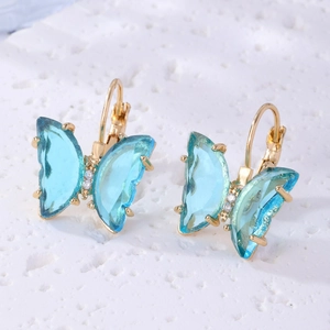 Detailed macro view of crystal butterfly studs with gold plating and blue wings