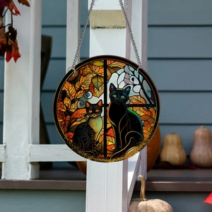 Detail of round acrylic pendant featuring two black cats and autumn leaves decoration