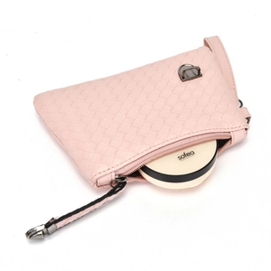 Detailed close-up of pink woven texture handbag with metal zipper and cosmetics inside