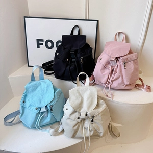 Collection of nylon backpacks in black, pink, blue, and cream on a display stand