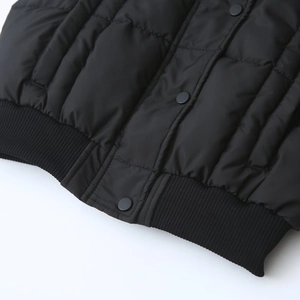 Dettaglio del gilet trapuntato nero con bordo elastico a coste e bottoni a pressione